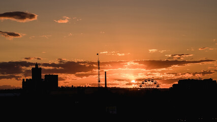 Naklejka premium Ferris wheel at sunset. Silhouette of the city in the evening.