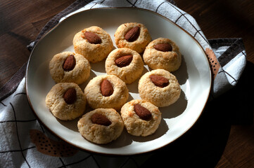 Cococnut cookies, with cream cheese and almonds in plate on wooden table with teatowel. Home kitchen sweets, baked. recipe
