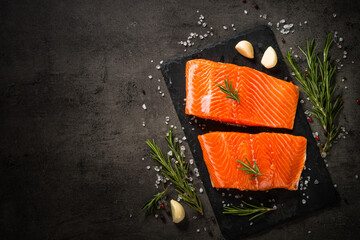 Salmon fish with ingredients at black table.