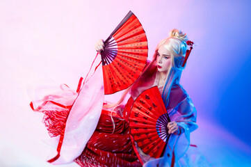 a woman in a geisha costume with fans sits on a white background