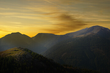 Berg mit Gipfelkreuz im Sonnenuntergang
