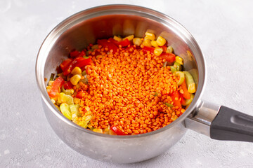 Cooking vegetable stew with lentils in a saucepan. Healthy food concept.