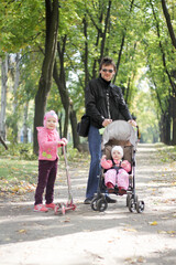 dad with two daughters for a walk in the autumn park