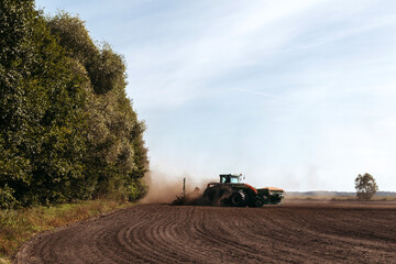 Big tractor is plowing field. The farmer works in field.