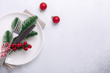 Christmas table place setting with empty white plate, candy canes, fir branch and cutlery with...