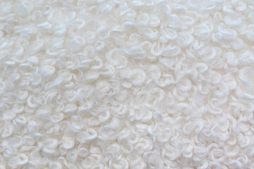 The texture of artificial white wavy curly wool. Abstract white background.