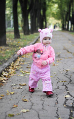 little girl in pink clothes is walking in the autumn park