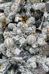 The white snow-covered tree is decorated with toys.