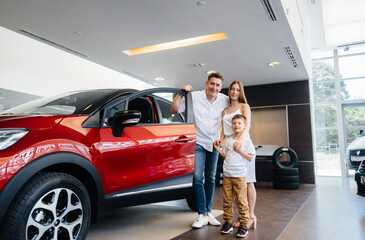 A happy young family chooses and buys a new car at a car dealership. Buying a new car