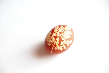 Painted Easter egg on a white background. Floral pattern on a red eggshell. Festive food.