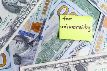 Yellow stick notes on an USD money background. Saving money for university concept