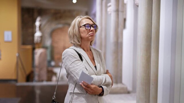 mature woman visitor in historical museum looking at art object