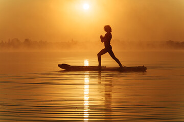 Relaxed man keeping balance on sup board during sunrise