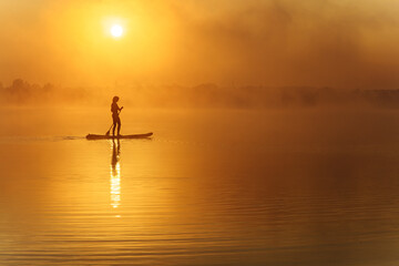 Silhouette of active man standing up on paddle board