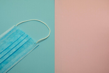Fototapeta na wymiar medical face mask on blue and pink background - concept image 
