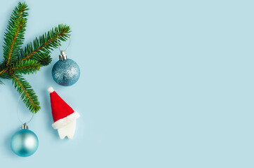 tooth in santa hat under christmas tree, fir on blue background. creative medical stomatology christmas card. Health care, dental hygiene concept. free space, text. flat lay