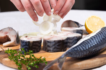 Obraz na płótnie Canvas the chef's hand sprinkles onions on mackerel with lemon