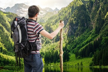 Hiking tourist with backpack from behind. Alps in background.
