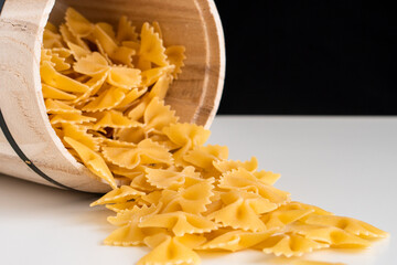Raw dry uncooked Farfalle pasta spaghetti noodle on white bowl wooden background for basil tomato pesto sauce Homemade Italian food organic whole wheat vegan spaghetti for a healthy meal