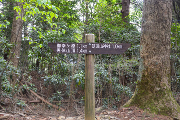 Tsukuba, Japan - April 30: A wooden signpost in the forest at Mount Tsukuba showing ‘Miyukigahara’ and 'Male mountain peak' to the left and ‘Tsukuba mountain shrine’ to the right. (April 30, 2018)