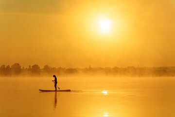 Silhouette of sportive man rowing oar on sup board