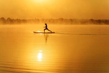 Young man balancing on sup board with paddle in hands