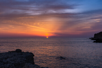 Beautiful orange sunset over the sea. The sun sets on the horizon. Relaxing sea landscape. Purple shades of sky and sea water. Sunset over the Black sea. The natural background.