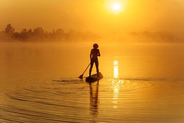Strong guy floating on paddle board during morning time