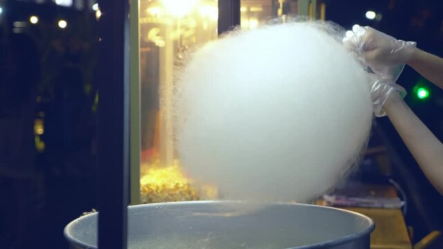 closeup. making cotton candy outdoors in the evening. hand in a protective glove