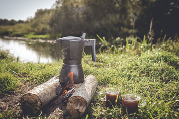 coffee maker on the fire in the forest and cups of coffee/coffee maker on fire at a picnic in nature on a sunny day
