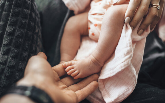 Upper view photo of a newborn baby's feet and her parents embracing her