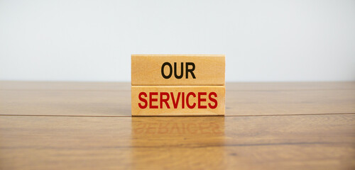 Wooden blocks form the text 'our services' on beautiful wooden table, white background. Business...