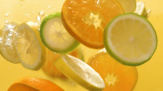 Slow motion shot of falling citrus fruits into water