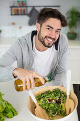 handsome man cooking at home preparing salad in kitchen