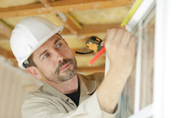 worker using tape measure the window in construction site