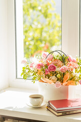 Fototapeta na wymiar light romance background. coffee cup with notepad and flowers bouquet on a window sill. love and romance concept