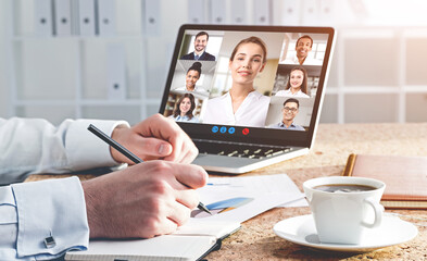 Man with coffee taking notes during his video chat