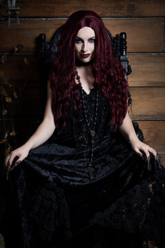 A young woman sits on a black gothic throne in a Halloween themed image