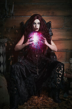 A woman sits on a gothic throne with a glowing orb in her hands in a Halloween themed image