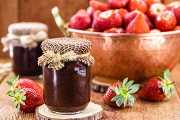 organic strawberry jam, handmade candy, with copper pot in the background with defocused fruits