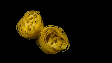 raw tagliatelle pasta isolated on black.