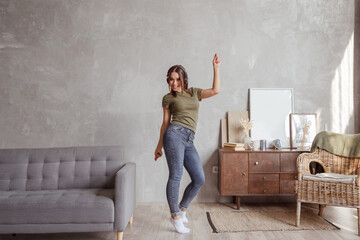 Young woman with wireless headphones dancing and listening to music at home