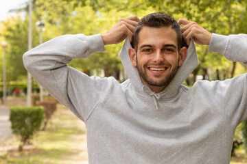 young man outdoors taking off his sweater