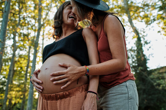 Closeup of a pregnant lesbian couple doing a photoshoot in a park