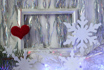 Red heart on photo frames with snowflakes and festive tinsel , side view - the concept of meeting your favorite new year holidays