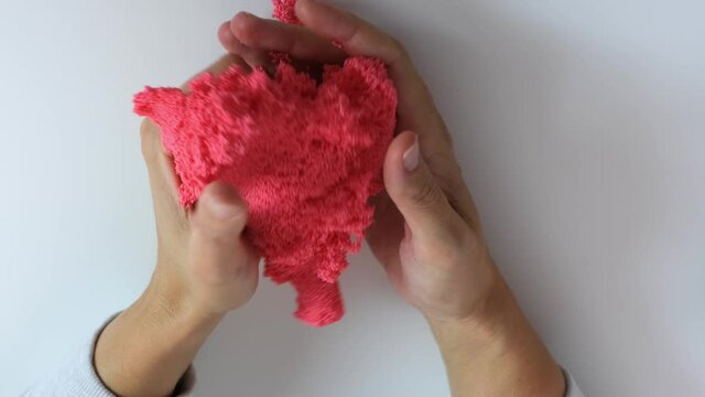 Hands crushing, squizing and crumpling pink plasticine, gum for hands with small balls inside, anti stress and relaxing game, close up