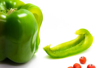 Green pepper with slice with red spot and berries on white isolated background
