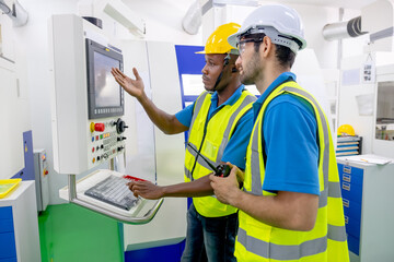 Two factory worker men discuss about operating machine with one point to monitor and other hold walkie talkie for communicate. Concept of good management system to support industrial business working.