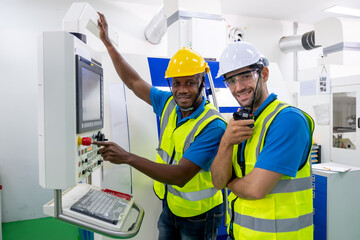 Two factory worker men with uniform stay with operating machine and look to camera. Main subject is African American man with concept of good management system to support industrial business working.