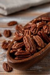 Roasted pecan nuts in a wooden bowl, close up appetizing view